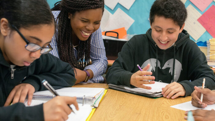 Teaching Fellow and Student laughing at table in the classroom of Knowles Teacher Initiative